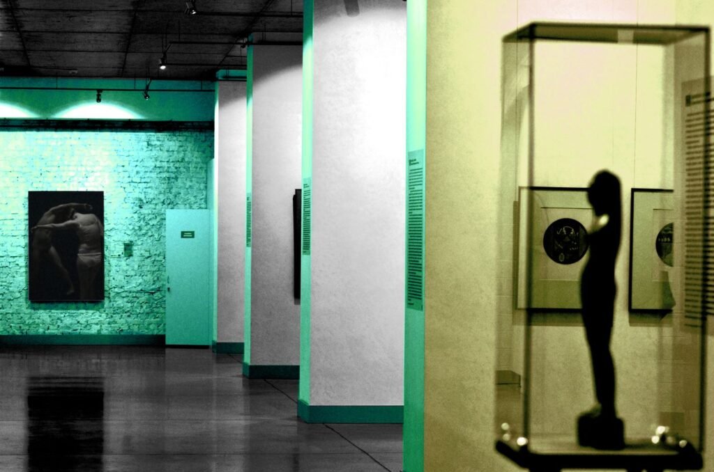 A gallery room lit in green and yellow with display cases