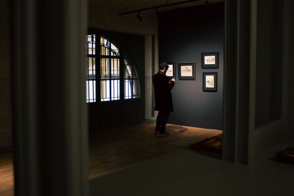 A dark gallery room with lit artwork on the walls