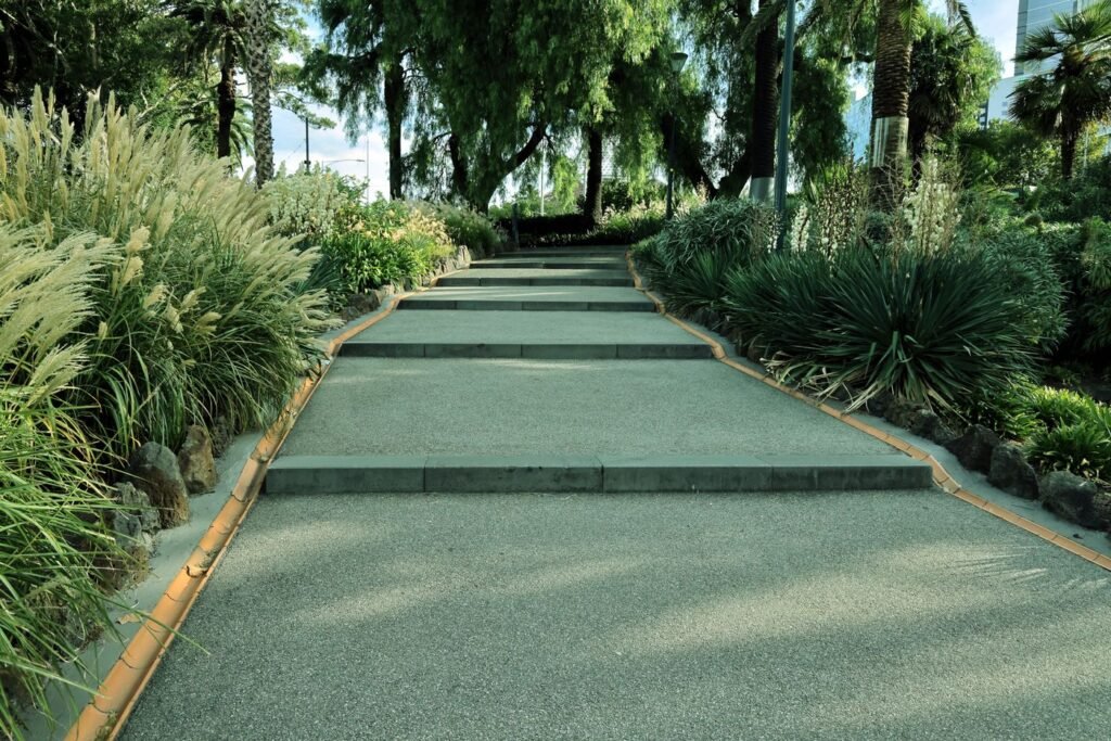 A quiet garden pathway lined with lush green plants and trees