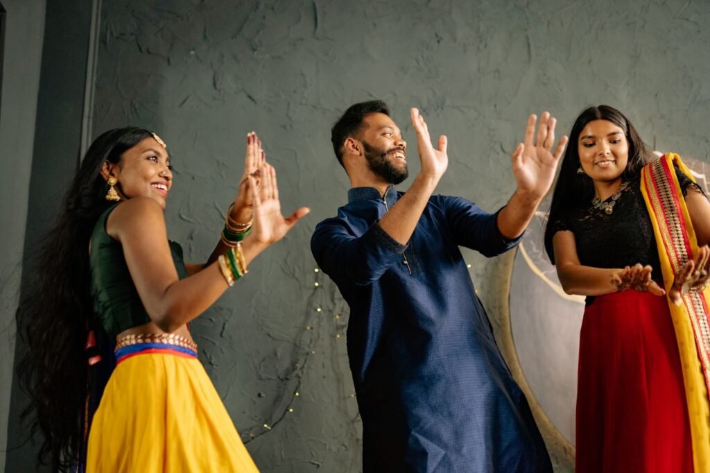Adults in colorful traditional Indian clothing dancing together at a celebration