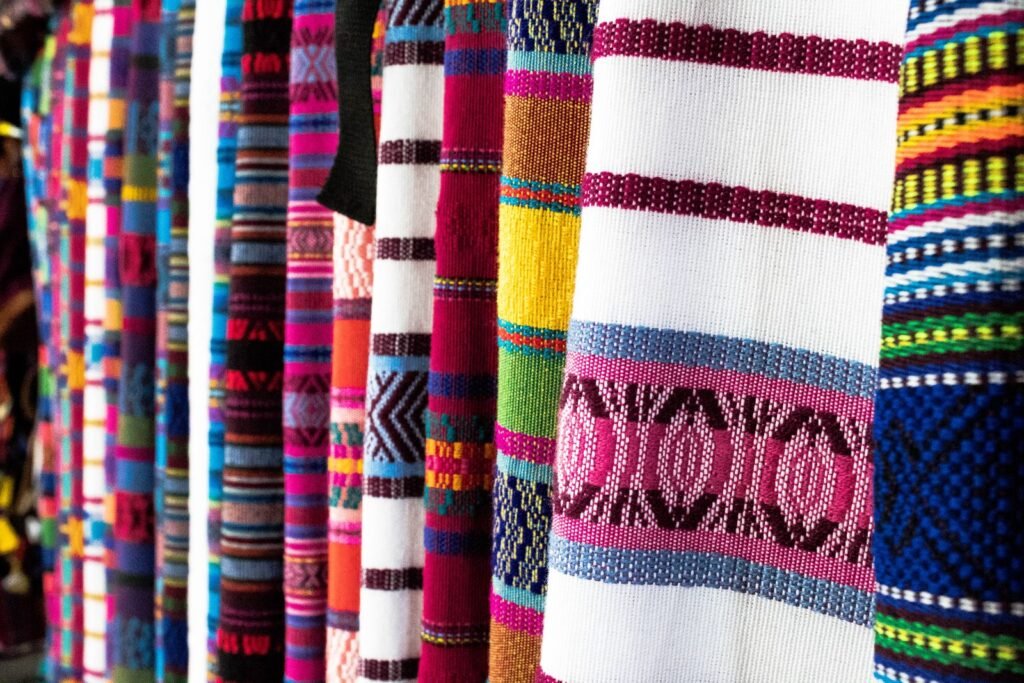 Brightly colored hand-woven Guatemalan textiles hanging side by side at a market