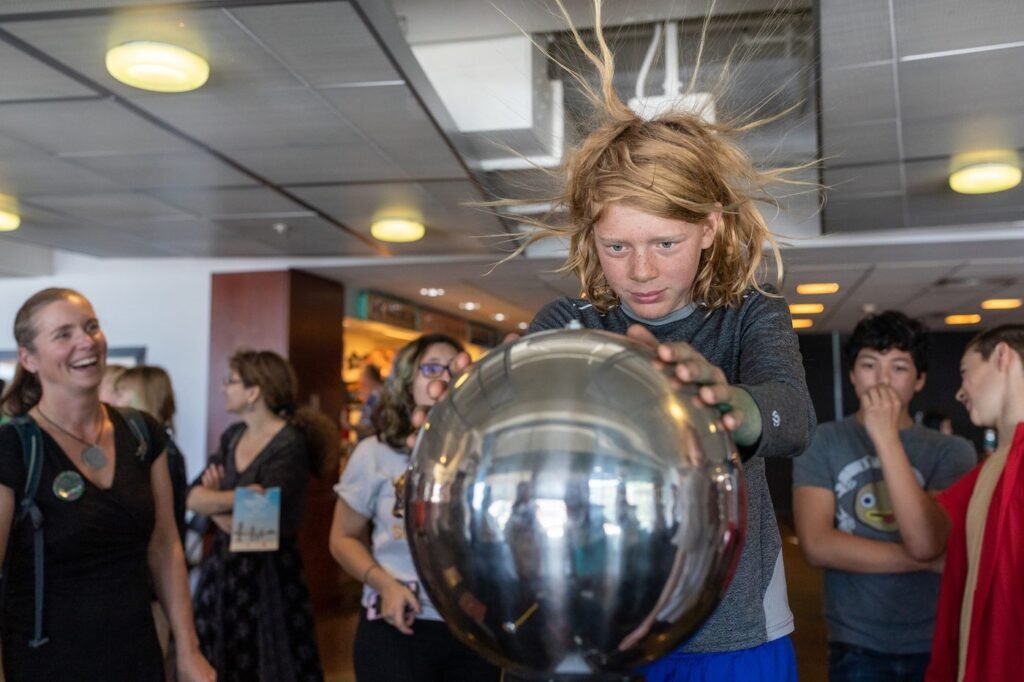 A child's hair standing on end from a static electricity sphere at the Bay Area Science Festival
