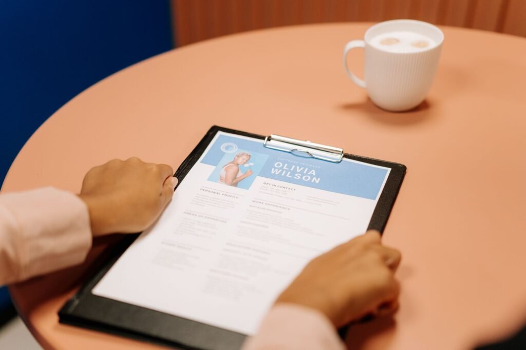 Hands holding a printed resume on a black clipboard at a table