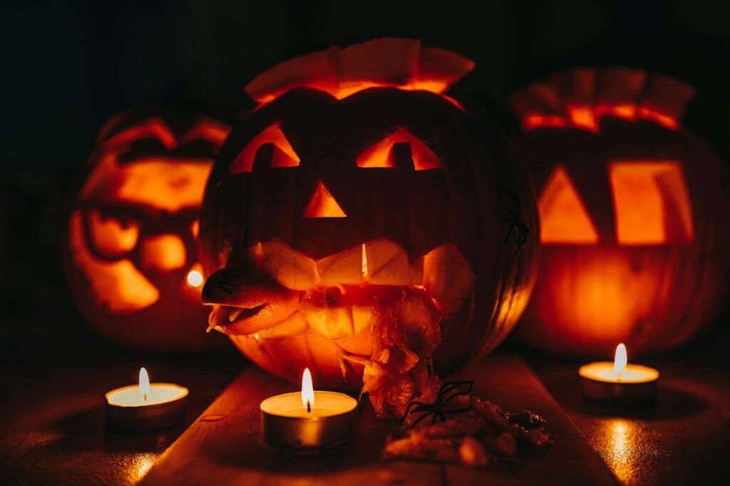 Three carved jack-o'-lanterns glowing beside tea lights