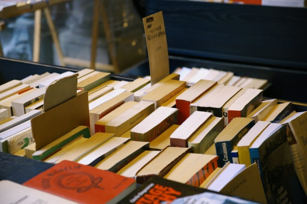 Secondhand paperbacks packed in a wooden crate at a bookseller stall, seen from above.