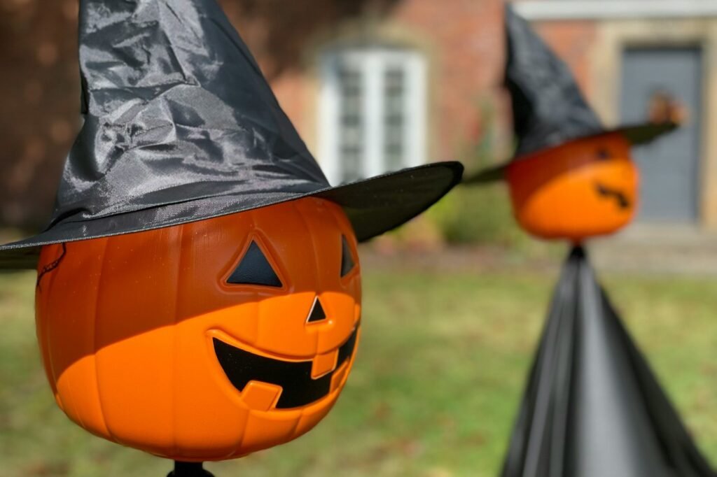 Jack-o-lantern pumpkin decorations wearing black witch hats on a lawn.