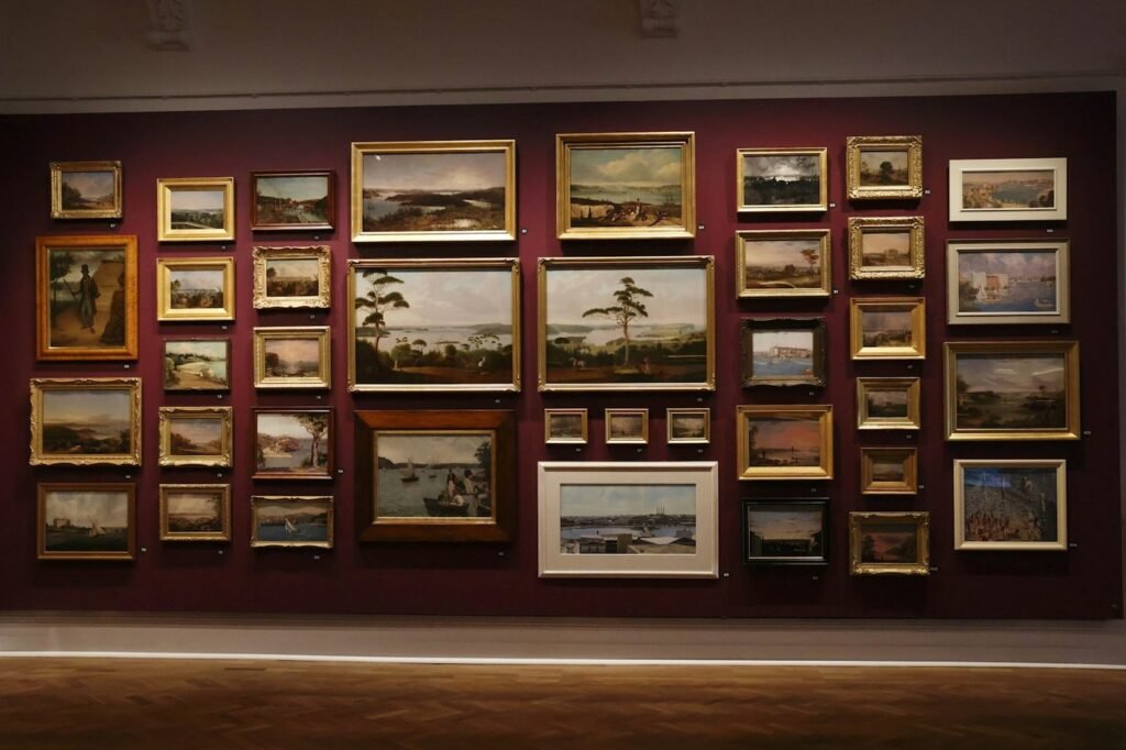A wall of gold-framed landscape paintings in a gallery.