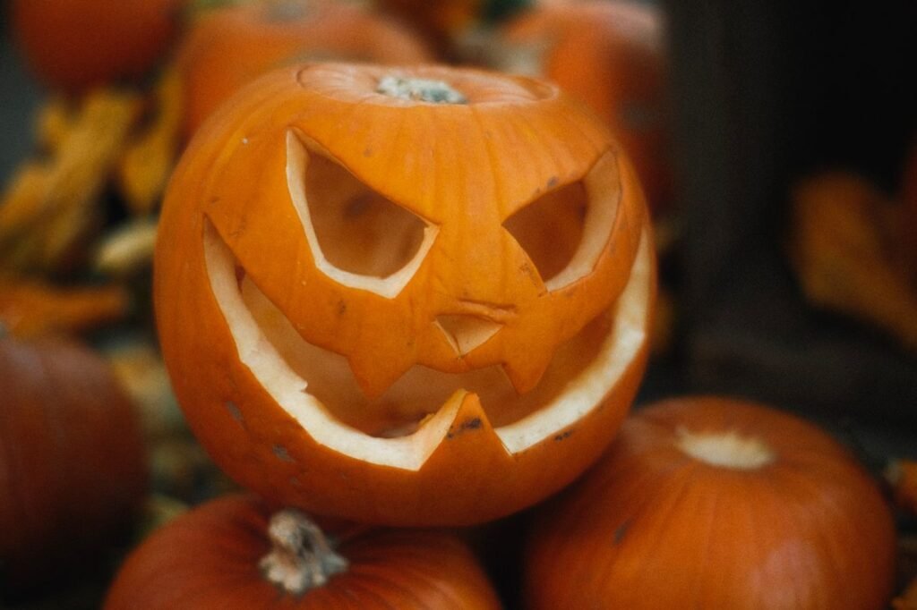 A carved jack-o-lantern surrounded by orange pumpkins.