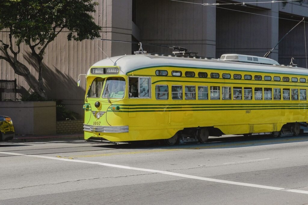 A yellow vintage F-line streetcar bound for the Ferries on a sunny San Francisco street.