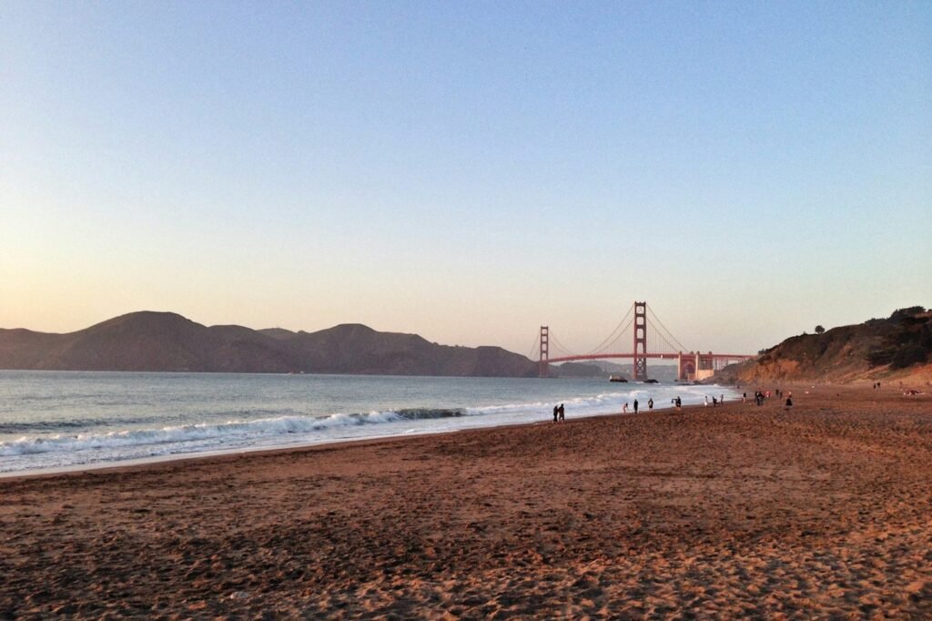 Baker Beach at dusk with the Golden Gate Bridge in the distance.