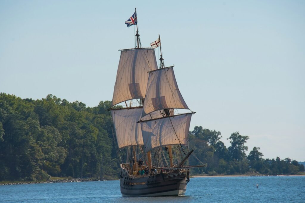 Tall-masted galleon sailing past a wooded shore