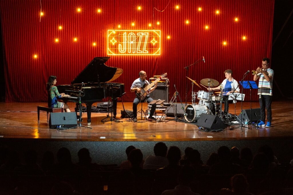 Jazz band performing in a dim room, photo by Alex Zamora on Unsplash