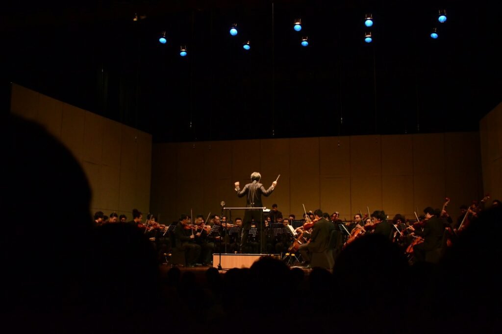 Conductor leading an orchestra on a dim stage