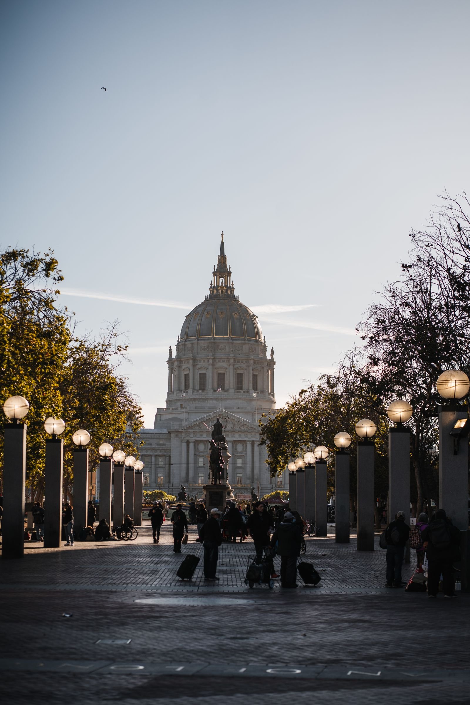 San Francisco City Hall at dusk with lit street lamps.