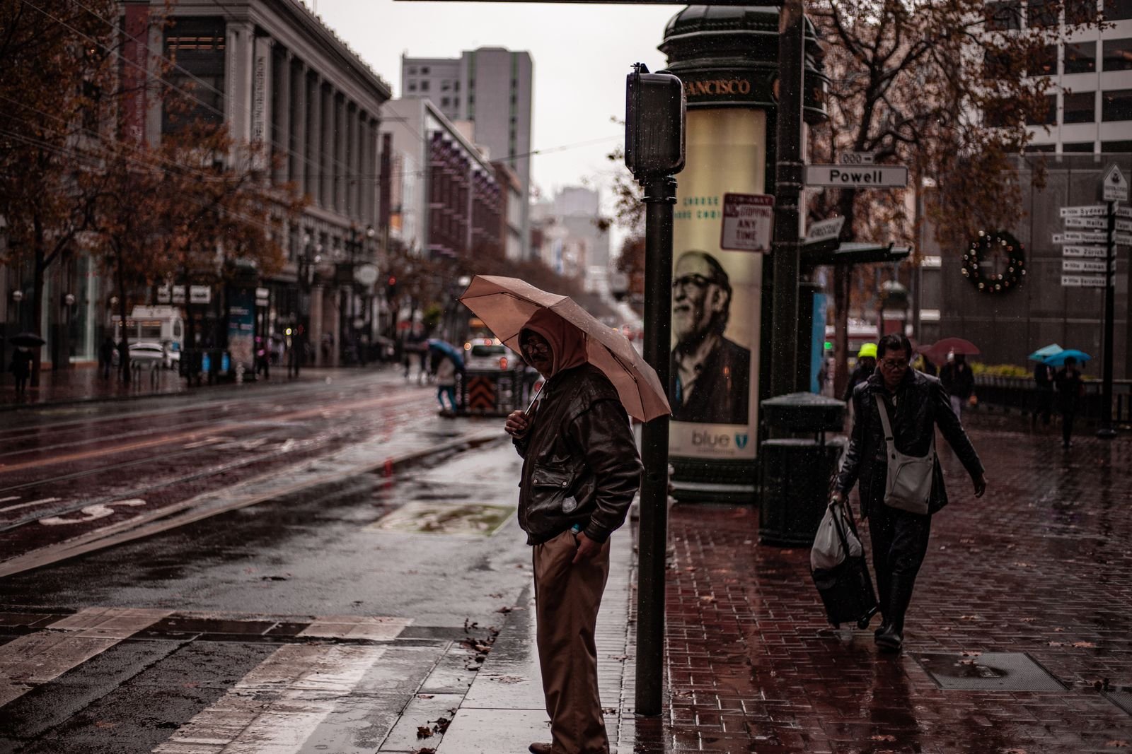 People with umbrellas on a wet San Francisco street.