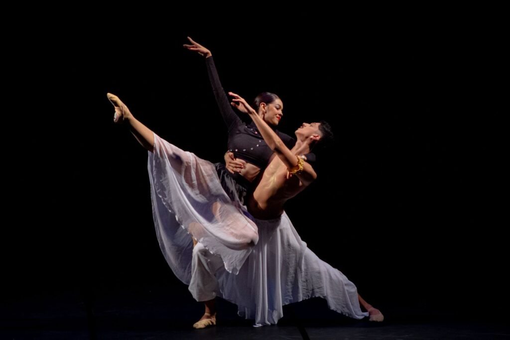 Two ballet dancers performing a lift on stage.