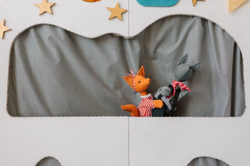 Two animal puppets performing in a small puppet theater.