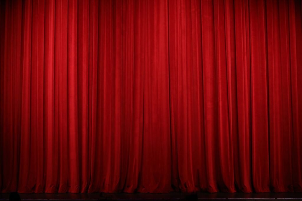 Red theater curtains drawn across a stage.