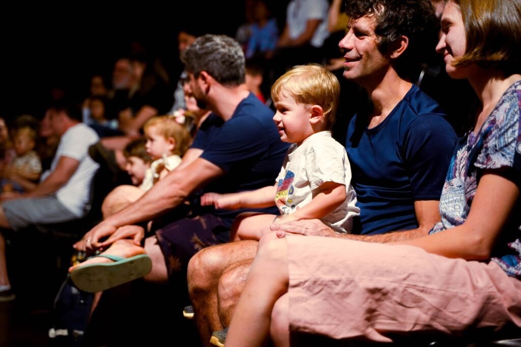A family audience watching a live show in a theater.