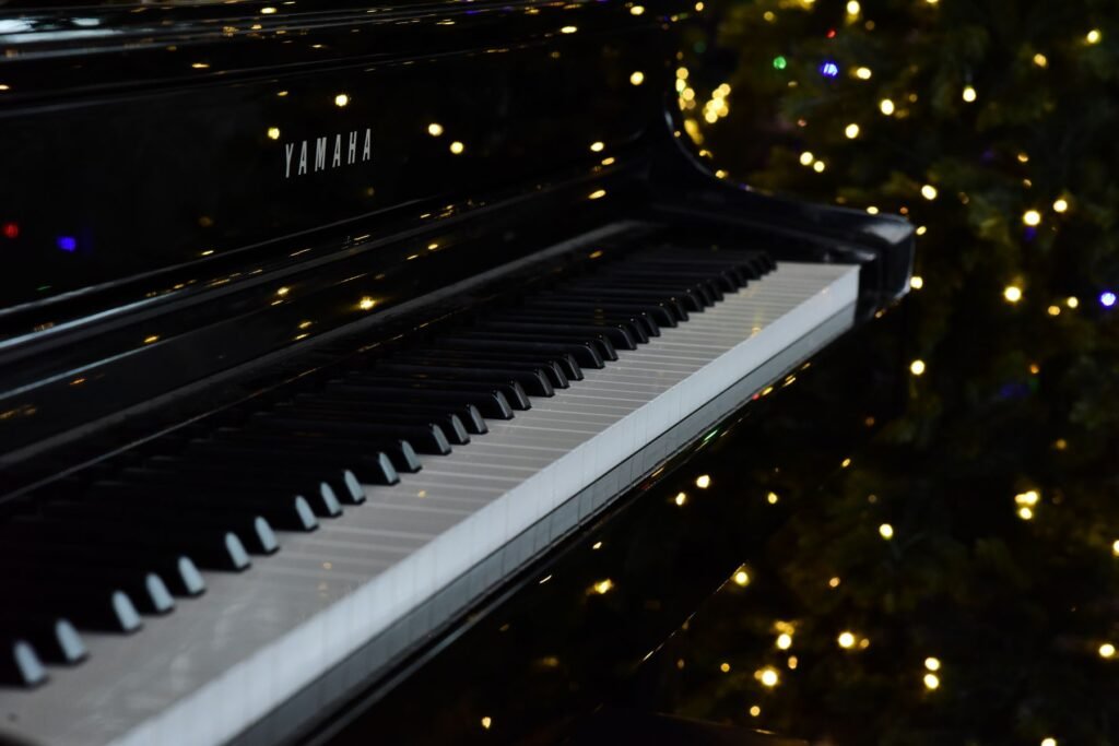 A grand piano keyboard with Christmas lights in the background.