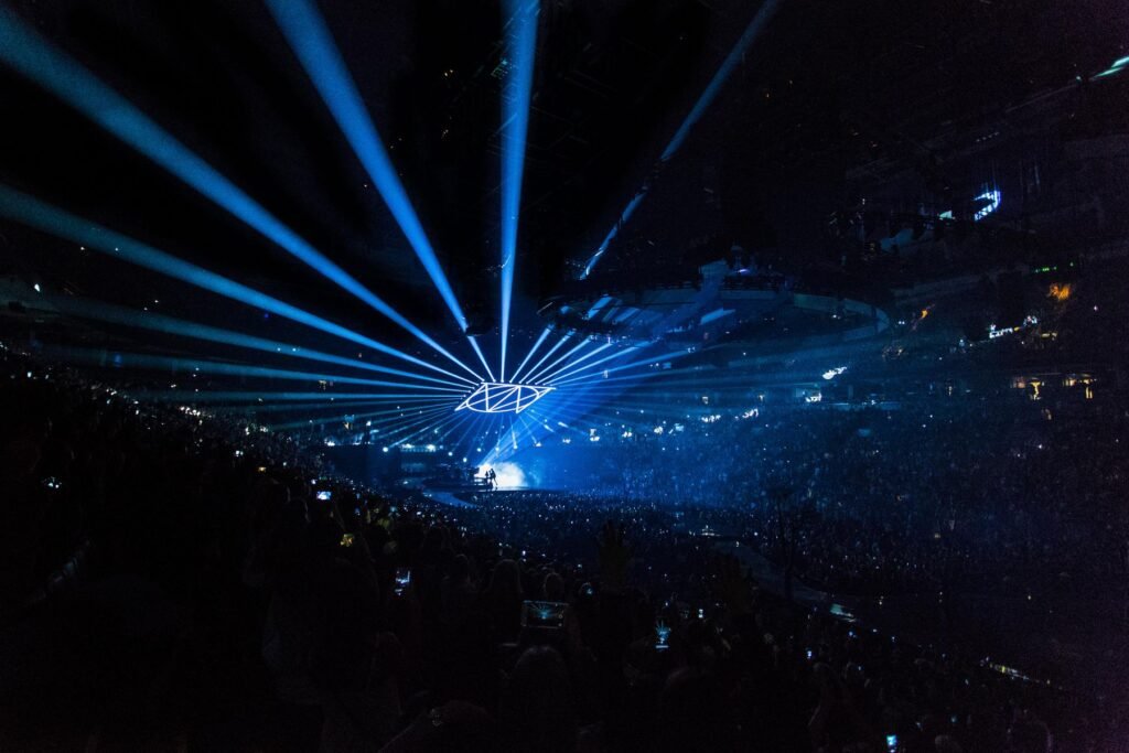 An arena concert crowd under a big light show.