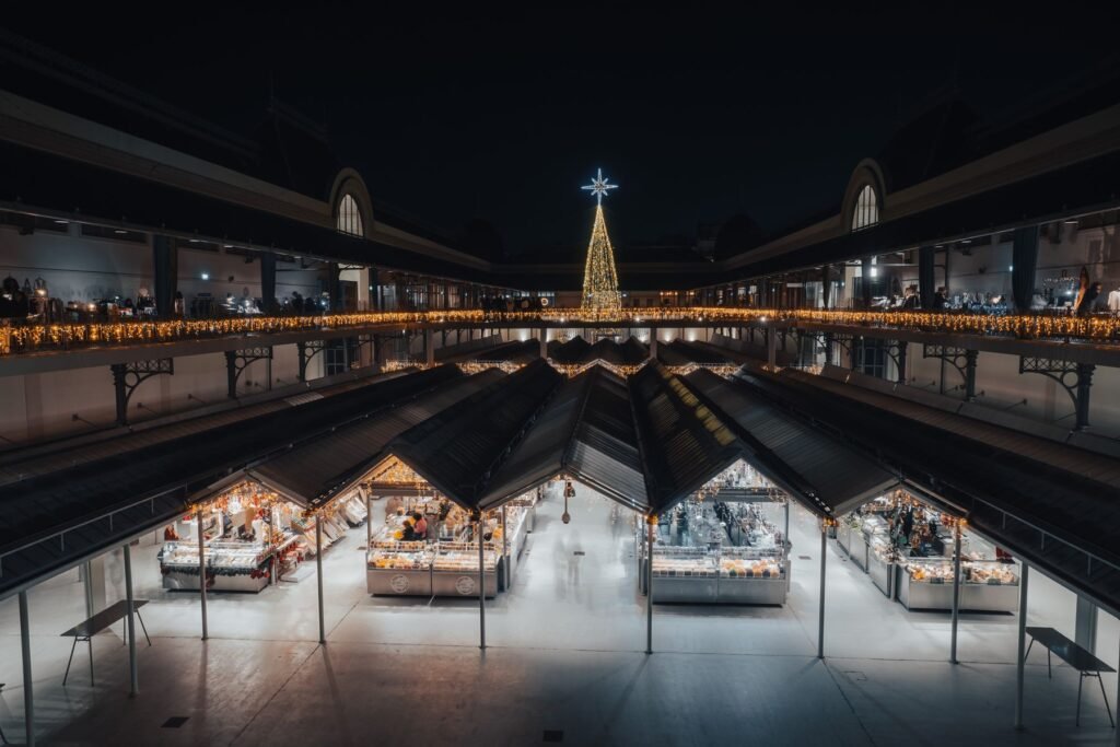 An indoor holiday market with Christmas lights at night.