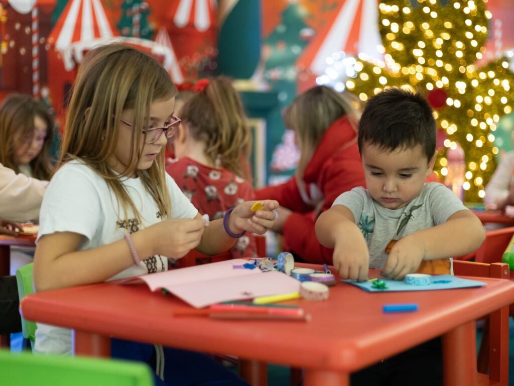 Children making Christmas decorations at a table.