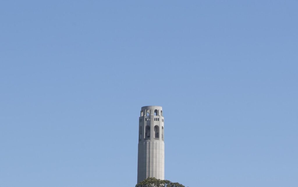 Coit Tower on Telegraph Hill above the rooftops of San Francisco, with the Transamerica Pyramid beside it