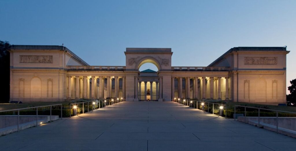 The California Palace of the Legion of Honor lit at dusk, with its colonnade and central arch
