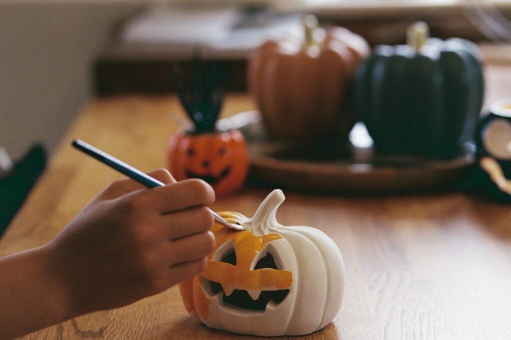 A hand painting a jack-o'-lantern craft on a wooden table