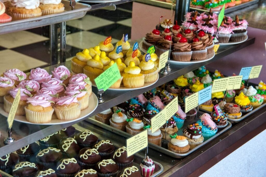 Bakery display case filled with colorful decorated cupcakes