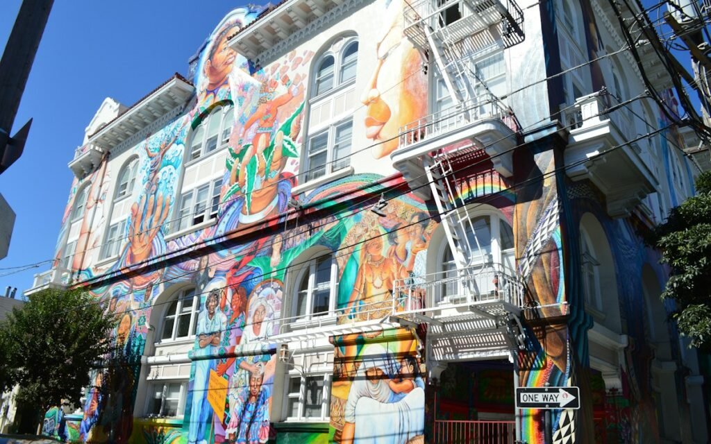 A building facade covered in a large colorful mural under a blue sky