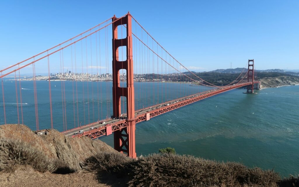 The Golden Gate Bridge from a rocky overlook on a clear day, with the city skyline in the distance