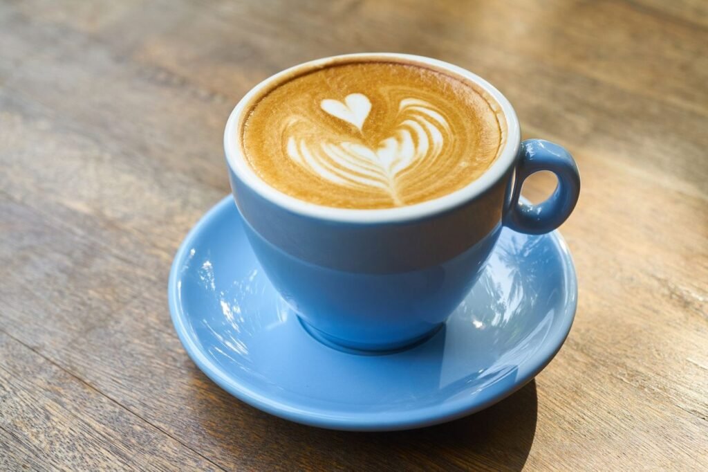 Latte with leaf latte art in a blue cup and saucer