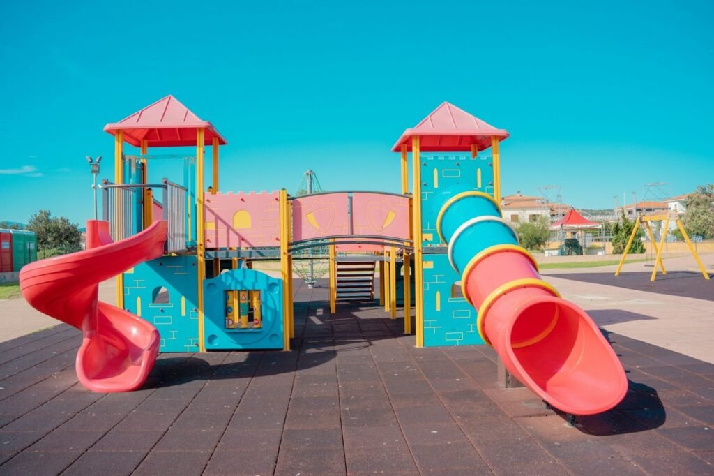 Bright modern playground with red tube slides on a paved urban lot