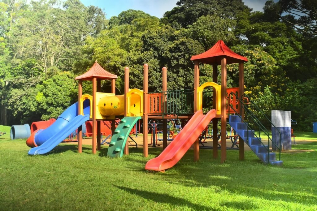 Colorful playground with slides surrounded by tall leafy trees