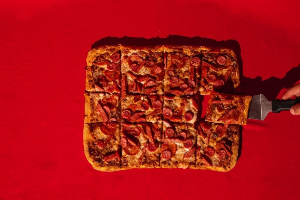 Square-cut rectangular pepperoni pizza on a red background