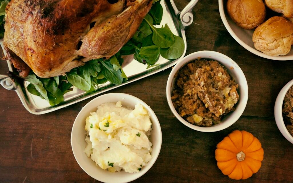 A Thanksgiving spread with roast turkey, stuffing, mashed potatoes and a small pumpkin