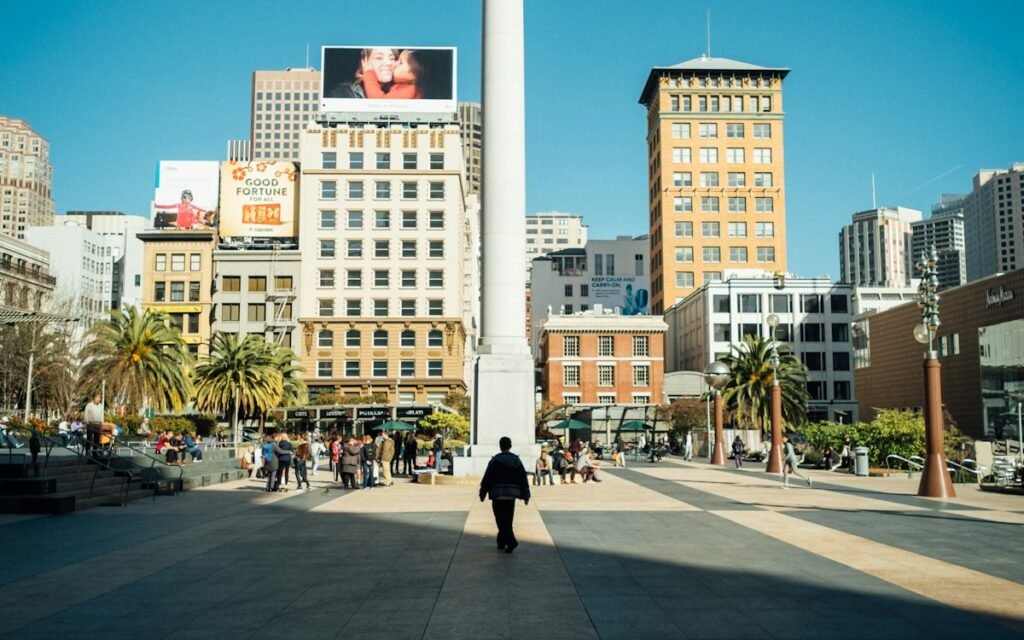 Union Square plaza in San Francisco on a sunny day, with palm trees and the tall monument column