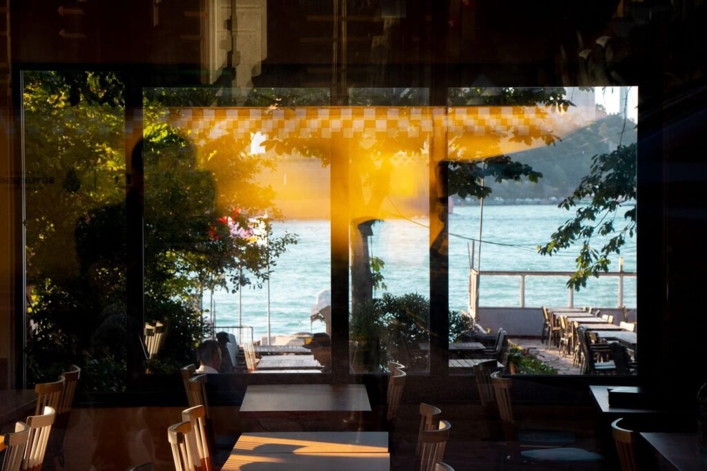 Restaurant dining room with tables facing large windows onto the water