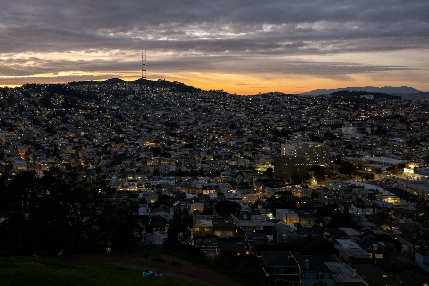 Hillside houses below Twin Peaks and Sutro Tower at sunset
