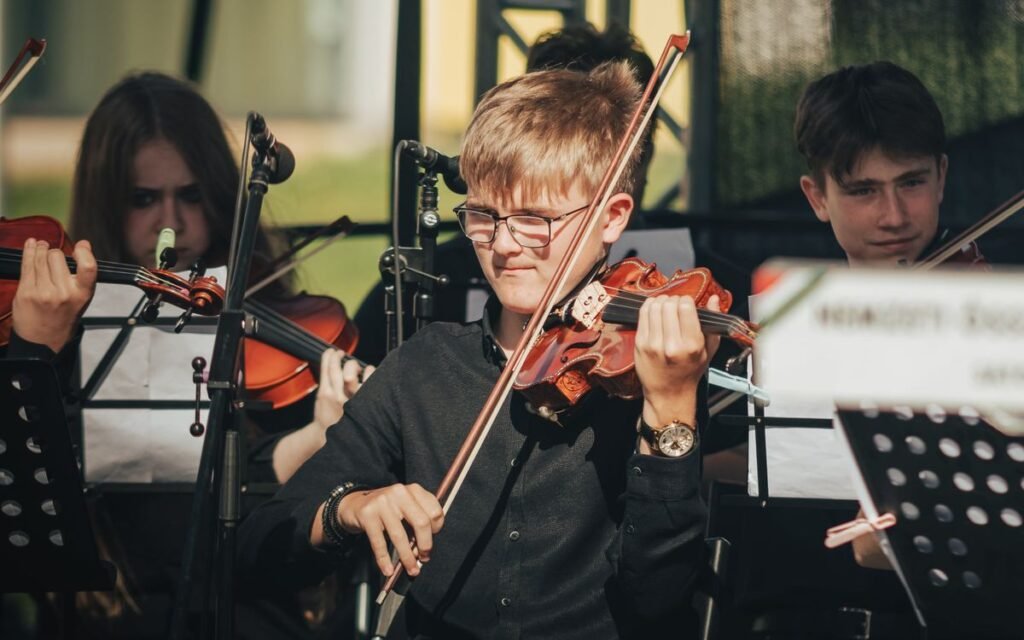 Young violinists in black playing at music stands