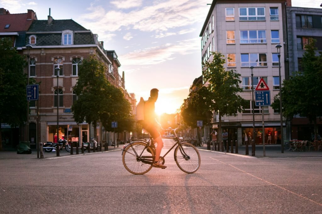 Cyclist riding across an open city street at sunset
