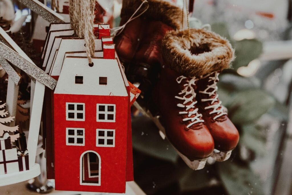 Handmade holiday ornaments, a red wooden house and a pair of tiny ice skates, hanging at a market stall