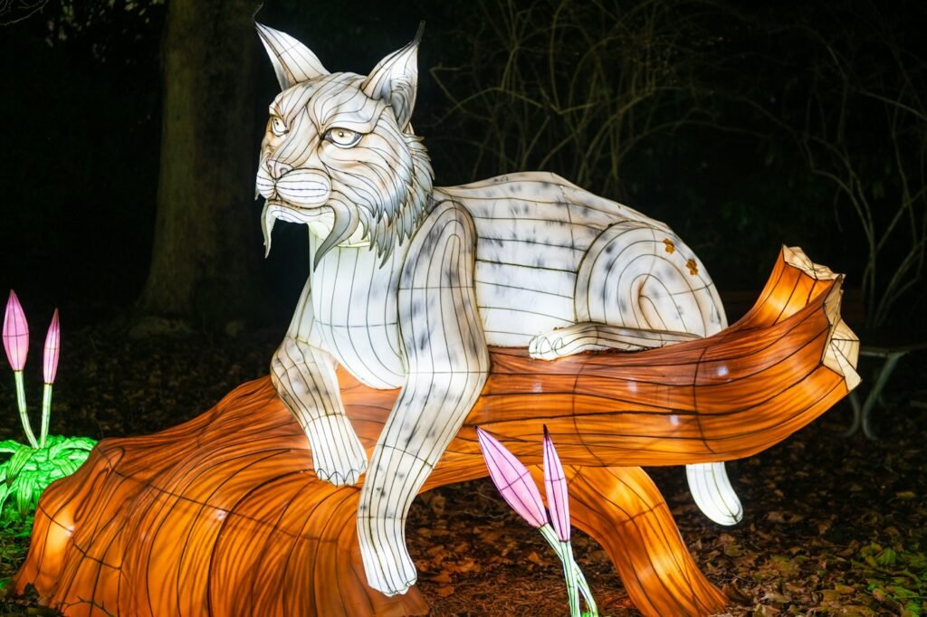 A glowing lantern sculpture of a lynx resting on a log at night